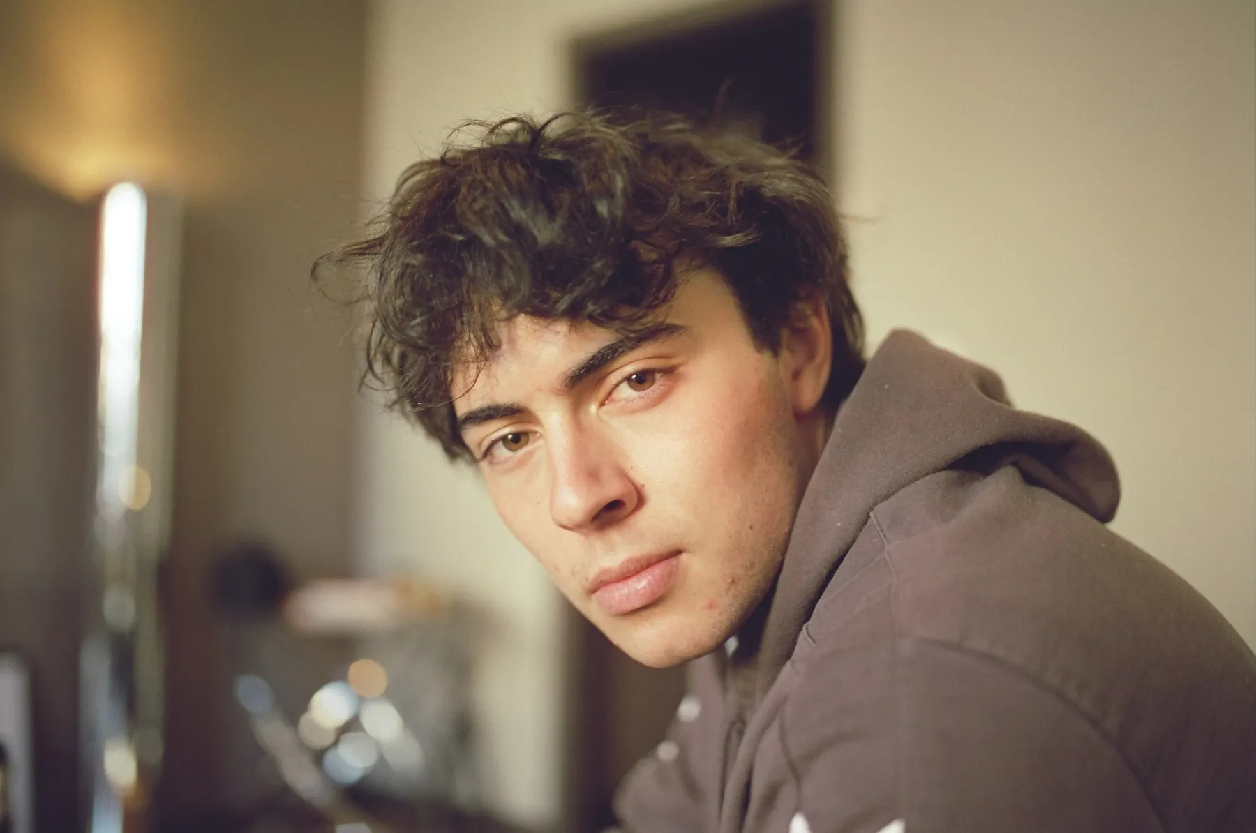 Film portrait of Luke in a brown hoodie, looking over his shoulder