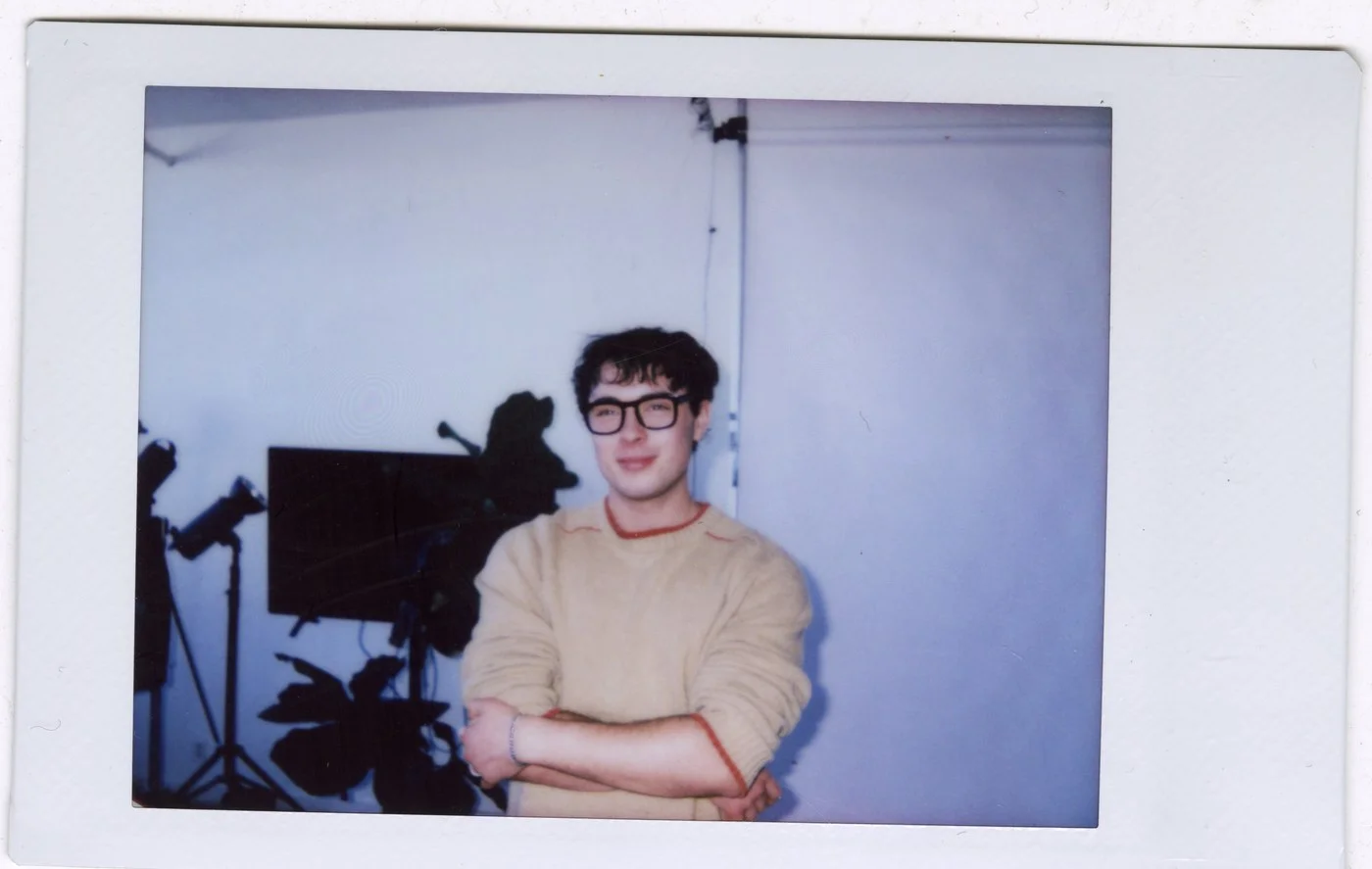 Instant photo of Luke Tava Rodriguez in a studio, arms crossed